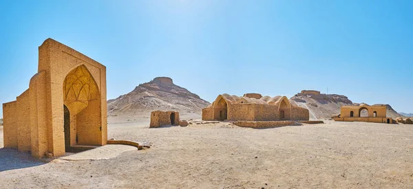 The desert grounds of Dakhma (Towers of Silence) ancient burial site with preserved khaiele ritual buildings, water cistern and burial towers on the hilltops on background, Yazd, Iran.