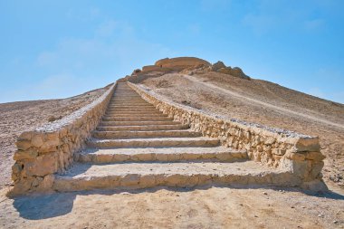 The long stone staircase leads to the hilltop, ending with ancient Zoroastrian burial structure - Tower of Silence (Dakhma), Yazd, Iran.