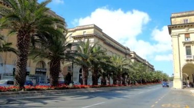 Floriana, Malta - 17 Haziran 2018: Yemyeşil yeşil avuç içi ve eski yapılardır ve hızlı sürme arabalar, 17 Haziran'da Floriana içinde St Anna Caddesi üzerinde doğal çiçek yatak.