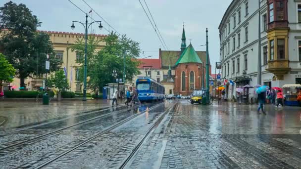 日にクラクフで 路面電車を背景に雨のビュー アッシジの聖フランシス教会にすべての聖人広場に沿って乗るクラクフ ポーランド 2018 — ストック動画
