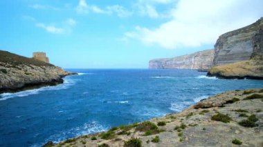 Kıyı şeridi ile fırtınalı denizde uzun boylu kayalık uçurum ve Gozo Adası - Xlendi Tower'ün en eski korunmuş gözcü bulunan aynı adlı köyde, Malta.