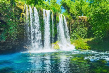The picturesque landscape around the Upper Duden Waterfall - the deep canyon is covered with lush greenery, providing shade and fresh air to the public park, Antalya, Turkey. clipart