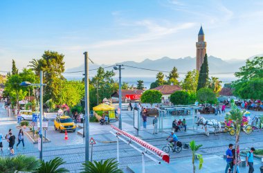 Antalya, Türkiye - 11 Mayıs 2017: Sokak Cumhuriyet Caddesi ile sahne üzerinde 11 Mayıs Antalya insanlar, yeşillikler, ortaçağ, Yivliminare Alaaddin Camii, at arabası ve Toros Dağları arka plan üzerinde yürüyen bir görünüm.