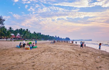 CHAUNG THA, MYANMAR - FEBRUARY 28, 2018: The sunset is perfect time to walk along the beach, enjoy the sound of tide and beauty of the sky, on February 28 in Chaung Tha. clipart