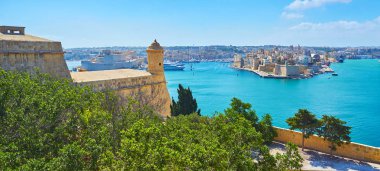 The green trees of Herbert Ganado Gardens hide the massive wall of St Peter and Paul counterguard, facing the Grand Harbour of Valletta with medieval fortresses of Birgu and Senglea, Malta. clipart