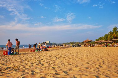 CHAUNG THA, MYANMAR - FEBRUARY 28, 2018: Lazy day on the beach with numerous street vendors, families of holidaymakers, children and bicycle rental point, on February 28 in Chaung Tha. clipart