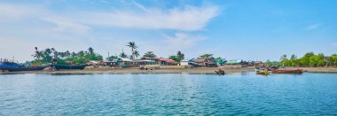Kangy nehir kıyısında eski tekneler ve kulübe aynı yanında bulunan Chaung Tha balıkçı köyü ile turizm tesisi, Bengal Körfezi, Myanmar karşı karşıya adlı.