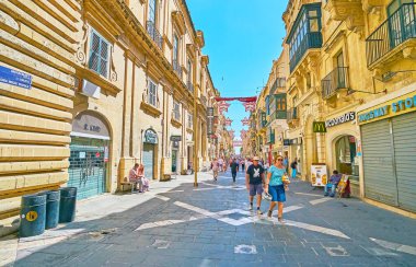 VALLETTA, MALTA - JUNE 17, 2018: The daily walk along Republic street, enjoying medieval architecture and visiting tourist stores and cafes, on June 17 in Valletta clipart