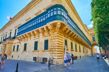 Valletta, Malta - 17 Haziran 2018: Eski tiyatro sokak menziller yan duvar boyunca büyük usta'nın Sarayı manzaralı doğal ahşap balkon ve Palace arch, 17 Haziran'da Valletta.