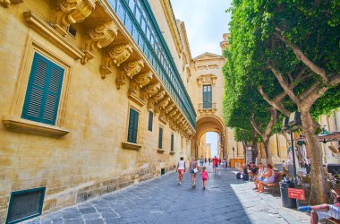 Valletta, Malta - 17 Haziran 2018: Eski Tiyatro Caddesi yan duvara oyulmuş taş ayrıntıları ve mesafe, Palace kemer 17 Haziran'da Valletta süslenmiş büyük usta'nın Sarayı manzaralı.