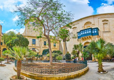 Valletta, Malta - 17 Haziran 2018: Panorama Prens Alfred's Courtyard Grandmaster'ın Sarayı, tarihi saat kulesi doğal yeşil bahçenin uzun ağaç, 17 Haziran'da Valletta görülür.