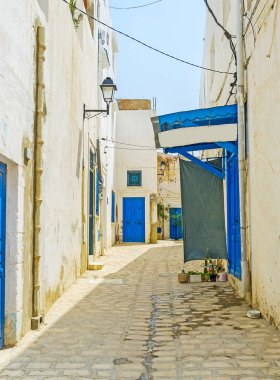 Parlak mavi kapı ve dış kil kanalizasyon boruları, Sousse, Tunus ile geleneksel beyaz dar boş sokakta Ortaçağ Medine evleri.