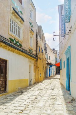 Dar sokakta Ortaçağ Medine otantik evleri, sıra ile dekore parlak mavi süs ızgara üstünde pencere eşiği, döşeme desenleri ve renkli kapı, Sousse, Tunus.
