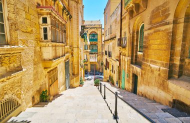 The stone staircase stretches along the narrow St Lucia street lined with old edifices, Valletta, Malta. clipart