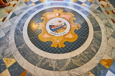 VALLETTA, MALTA - JUNE 17, 2018: The mosaic Coat of Arms of Malta decorates the floor of the corridor in Grandmaster's Palace, on June 17 in Valletta. clipart