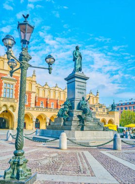 Turist grupları ve Genç çiftler Krakow popüler buluşma noktası Adam Mickiewicz Main Market Square üzerinde anıtıdır