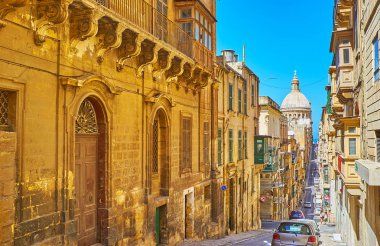 Valletta, Malta - 17 Haziran 2018: Yürüyüş dar eski nane inişlerde ve tırmanıyor ve dev bir kubbe Carmelite kilise ve tarihi konaklar, 17 Haziran'da Valletta bir görünüm ile sokak.
