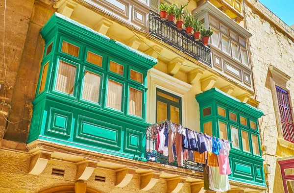 The bright green twin Maltese balconies with drying clothes between them, Old Mint street, Valletta, Malta.