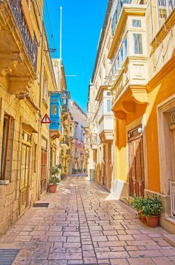Eski yaşam binalar, gölgeli Hilda Tabone sokak dar dekore renkli Malta balkonlu ve çiçekler tencere Road, Birgu (Vittoriosa), Malta.