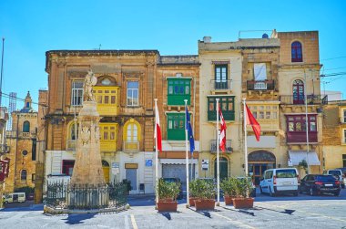 Taş Zafer Anıtı aynı adlandırılmış Meydanı (Misrah IR-Rebha), kafe ve restoranlar, Birgu (Vittoriosa), Malta ile tarihi Konakları çevrili süsle..