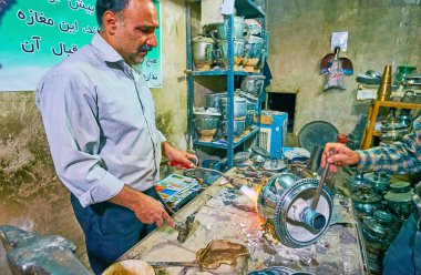 Kashan, Iran - 22 Ekim 2017: Master onarır ve eski bir paslanmaz çelik semaver kadar temizler Kapalıçarşı, 22 Ekim: Kashan içinde yer alan küçük atölye çalışmasında, yazıcı, çekiç ve diğer araçları kullanarak