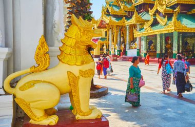 YANGON, MYANMAR - FEBRUARY 27, 2018: The golden statue of chinthe (leogryph) guards the entrance to the Image House of Shwedagon Zedi Daw, on February 27 in Yangon. clipart