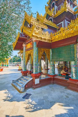 YANGON, MYANMAR - FEBRUARY 27, 2018: Beautiful porch of Tharrawaddy Min Bell House, ornate columns with mirror pieces, supporting the pyatthat roof, Shwedagon complex, on February 27 in Yangon. clipart