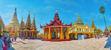 YANGON, MYANMAR - FEBRUARY 27, 2018: Panorama with main Shwedagon stupa, Gautama Buddha Image House, Sacred Hair Relic Washing Well and other shrines along the Northern alley of the complex, on February 27 in Yangon clipart