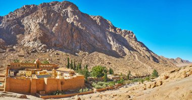 The rocky mountains around St Catherine Monastery serve as the perfect viewpoint, observing this fortified complex, standing in gorge, Sinai, Egypt. clipart