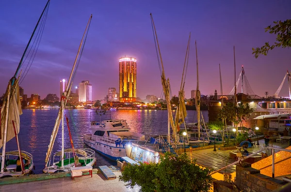 2017年12月23日 在尼罗河海滨路堤的傍晚 杰济拉岛的照明高楼在 Felucca 船后面 停泊在小造船厂 在12月23日在开罗 — 图库照片