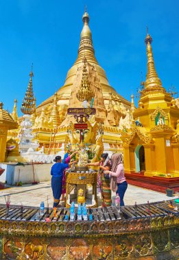 Yangon, Myanmar - 27 Şubat 2018: Budist adanmışlar gerçekleştirir su dökerek ayini Shwedagon Pagoda Buda'nın heykeli üzerinde 27 Şubat Yangon içinde mum ve tütsü sopa üzerinde ön plan, yanan.