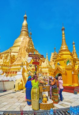 Yangon, Myanmar - 27 Şubat 2018: Budist adanmışlar Buda heykeli üzerinde 27 Şubat Yangon içinde arka plan üzerinde büyük altın stupas ile Shwedagon Pagoda içinde banyo ritüeli gerçekleştirmek