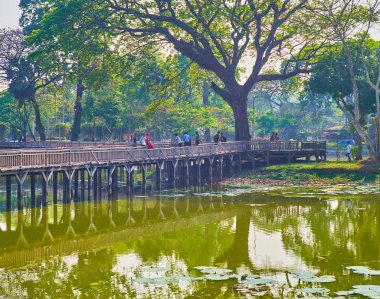 Yangon, Myanmar - 27 Şubat 2018: Kandawgyi Gölü dolgu eski ahşap köprü ve yayılan htanaung (akasya leucophloea) ağacı üzerinde 27 Şubat Yangon yapılan bir manzaralı boyunca keyifli günlük yürüyüş.