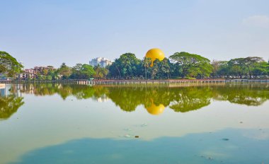 Mavi gökyüzü ve yeşillikler Park gölün kıyısında, Yangon, Myanmar Kandawgyi Gölü açık yüzeyine yansıtır