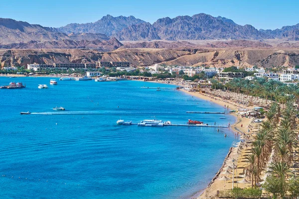 Sıcak kum plaj, Sharm El Maya gölgeli palmiye ağaçları ile kaplı ve Sina çöl kayalarla, Sharm El Sheikh, Mısır çevrili.