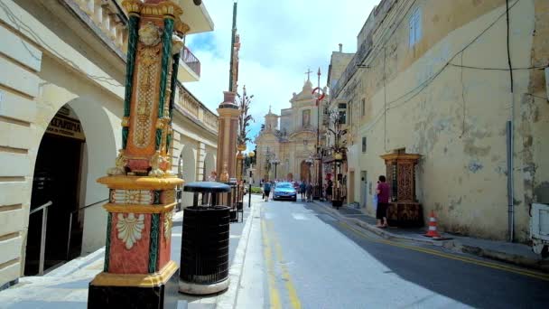 马耳他拉巴特 2018年6月16日 老城狭窄的街道 两旁有历史性的豪宅 装饰着城市盛宴的柱子 圣保罗教堂的门面出现在背景上 6月16日在拉巴特 — 图库视频影像