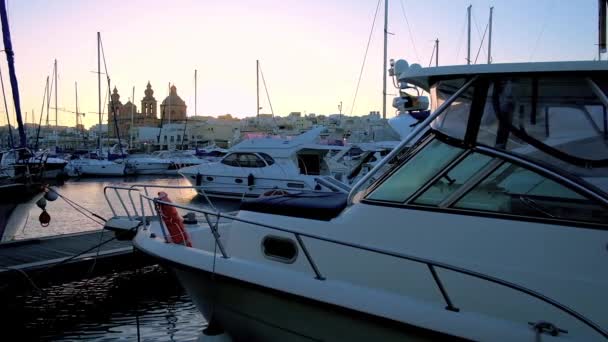 日落在 Msida 游艇码头与豪华游艇和小船 教区教堂高耸在城市天际 马耳他 — 图库视频影像