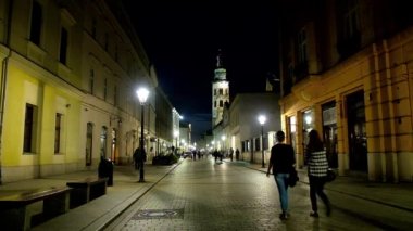 Krakow, Polonya - 12 Haziran 2018: Akşam yürüyüşüne arka plan üzerinde 12 Haziran Krakow yumuşak aydınlatma ve St Andrew Church of uzun çan kulesi ile Grodzka Caddesi boyunca.