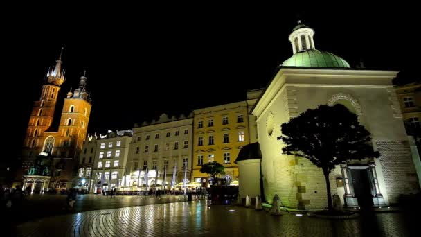 マーケット広場 そっと照らされた聖マリア大聖堂と聖アダルベルト教会 クラクフ ポーランドの人々 を歩いてのシルエット — ストック動画