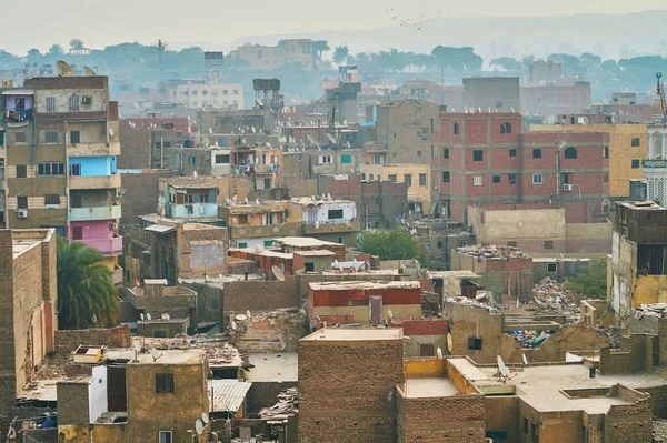 The urban slums in Islamic Cairo district: dense partly unfinished housing of dark earthen brick with heaps of garbage on the roofs and hundreds of satellite dishes, Egypt.