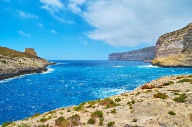Kıyı şeridi ile fırtınalı denizde uzun boylu kayalık uçurum ve Gozo Adası - Xlendi Tower'ün en eski korunmuş gözcü bulunan aynı adlı köyde, Malta.