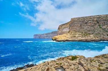 Tembel sular uzun boylu kayalık uçurum, yumrulu deniz manzaralı Xlendi sahil turistik köy boyunca yürümek ve bulutlar, Gozo Adası, Malta hareketli hızlı.