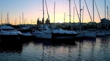 Yat Limanı görünüm üzerinde yat yelken ve Msida Parish Kilisesi silhouettes son günbatımı ışınları, Malta içinde.
