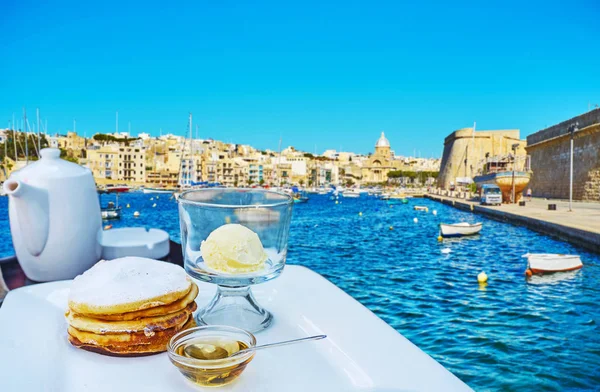 The breakfast at Marina of Kalkara with sweet pancakes, ice cream, maple syrup and black tea, Malta.