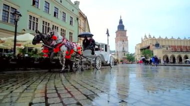 Krakow, Polonya - 13 Haziran 2018: Su birikintileri Main Market Square, kaldırımda şehir simge (City Hall Tower ve Cloth Hall) ve Binicilik atlı arabaları, 13 Haziran Krakow yansıtmak.