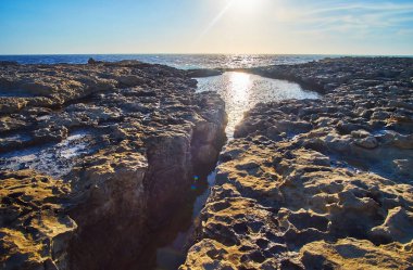 Girintili kayalık sahil San Lawrenz güneş ve gökyüzü yansıtan ve kontrast fırtınalı deniz suları, Gozo Adası, Malta yapma küçük sakin ve sessiz önemsizden içinde zengin.