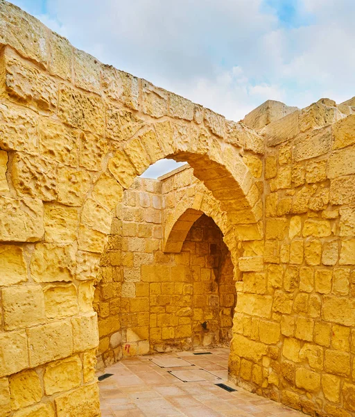 Walk the narrow curved streets of Rabat Citadel with tall stone walls and arched passes, Victoria, Gozo Island, Malta.