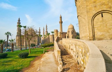 Bab Al-Azab Gate Selahaddin Eyyubi Kalesi sundurma yeşil bahçe manzaralı ve uzun boylu Salah El-Deen meydanında cami minarelerinin boyunca yürümek (Sultan Hassan, Al Rifai' ve Al-Mahmoudia), Kahire, Mısır.