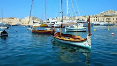 Senglea, Malta - 19 Haziran 2018: Doğal ahşap luzzu tekne Vittoriosa Marina dalgalar üzerinde arka plan üzerinde Ortaçağ Birgu city ile 19 Haziran Senglea tarihinde sallanan.