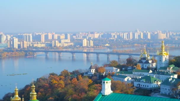 Sledujte mlhavé řeku Dněpr s mosty, podzimní zeleně podél břehu a kostel Narození Panny Marie z nižší (mnohem) jeskyně z Kyjeva Pechersk Lavra kláštera, Ukrajina.